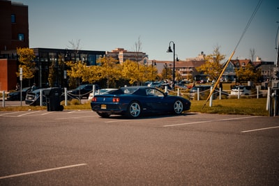 During the day, blue porsche 911 parked in a parking lot
